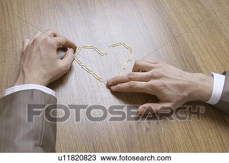 Business man rearranging paper clips in to heart on desk View Large Photo Image Stock Image - Business man rearranging paper clips in to heart on desk. Fotosearch