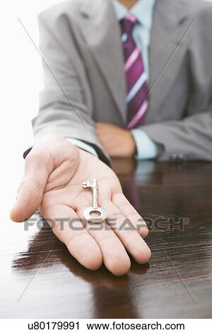 Stock Image - Businessman holding key, close-up. Fotosearch