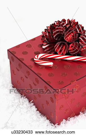 Stock Image - Candy cane and Christmas gift on snow. Fotosearch