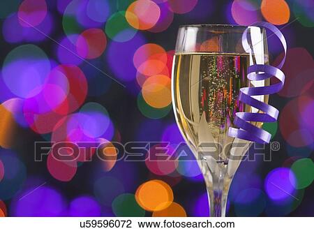 Stock Image - Champagne glass with ribbon on colorful background. Fotosearch