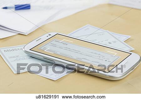 Stock Image - Cheque and cell phone lying on table. Fotosearch