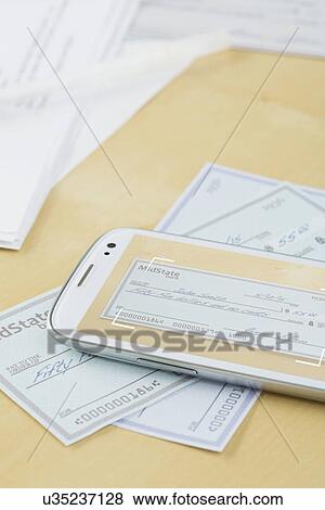 Stock Photo - Cheque and cell phone lying on table. Fotosearch