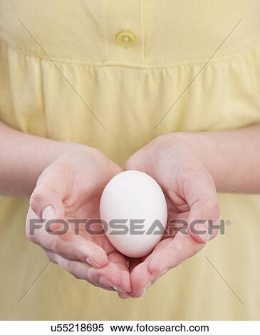 Stock Photography - Close-up of girl (10-11) holding egg. Fotosearch