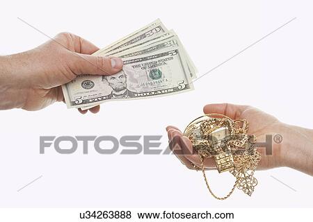Stock Photo - Close up of hands exchanging banknotes and gold jewelry, studio shot. Fotosearch