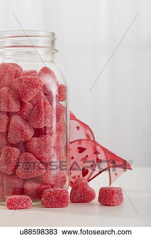Stock Image - Close-up of jar full of red, heartshaped candy. Fotosearch