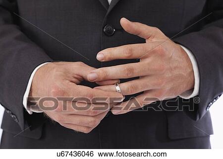 Stock Photograph - Close-up of man removing wedding ring from finger. Fotosearch