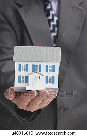 Stock Photo - Close up of man's hand holding model house. Fotosearch
