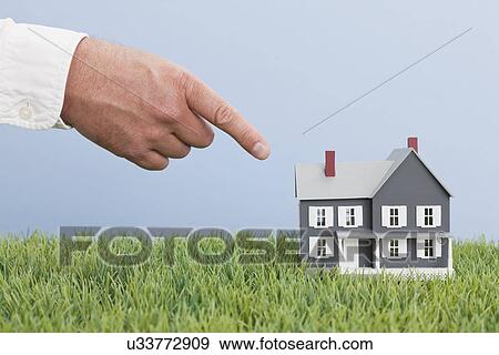 Stock Photo - Close up of man's hand pointing on model house. Fotosearch