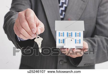 Stock Photo - Close up of man's hands holding model house and key. Fotosearch