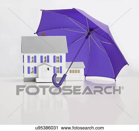 Stock Image - Close up of model house under umbrella. Fotosearch