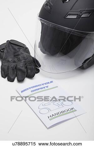 Stock Photography - Close up of motorcycle helmet, leather gloves and safety guideline book, studios shot. Fotosearch
