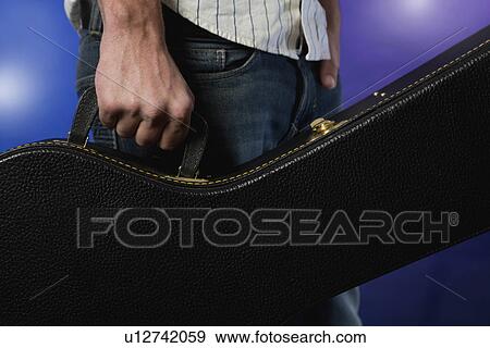 Close up of musician holding guitar case View Large Photo Image Stock Photo - Close up of musician holding guitar case. Fotosearch