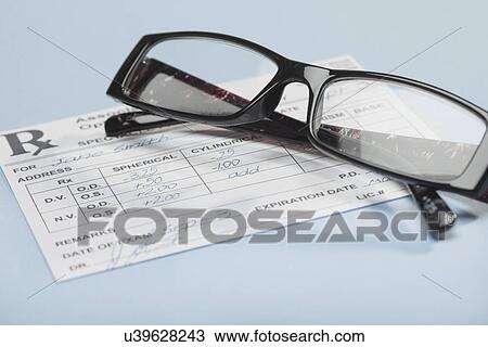 Stock Image - Close up of reading glasses on prescription, studio shot. Fotosearch