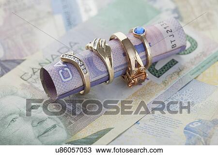 Stock Image - Close up of rings and banknotes, studio shot. Fotosearch