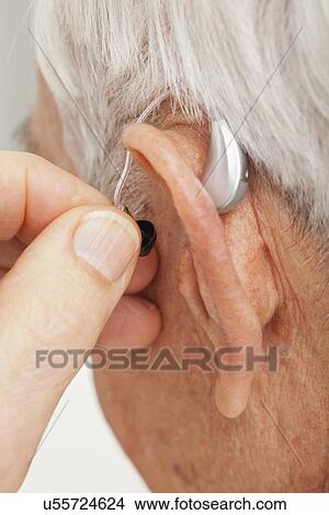 Picture - Close up of senior man's ear with hearing aid. Fotosearch