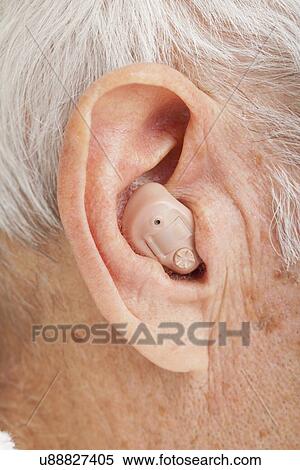 Stock Photography - Close up of senior man's ear with hearing aid. Fotosearch