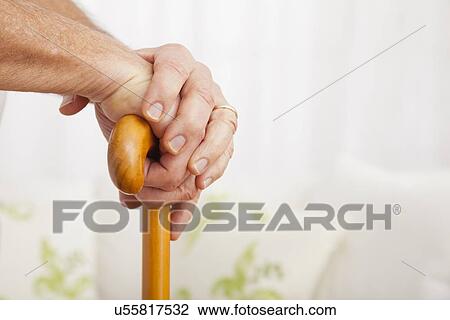 Stock Image - Close up of senior man's hands, leaning on cane. Fotosearch