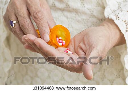 Stock Photo - Close-up of senior woman's hands with pills bottle. Fotosearch