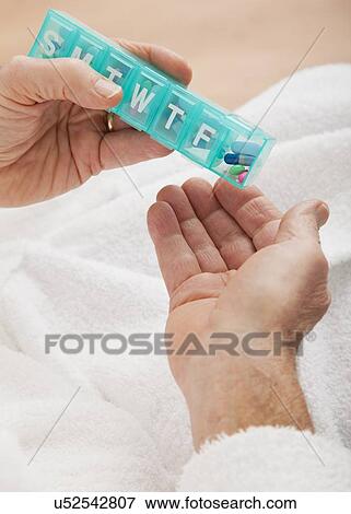 Stock Photo - Close up of senior's hands taking pill from pill organizer. Fotosearch