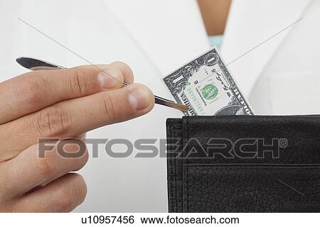 Stock Photograph - Close-up of woman holding one dollar bill via tweezer. Fotosearch