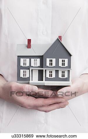 Stock Photo - Close up of woman's hands holding model house. Fotosearch