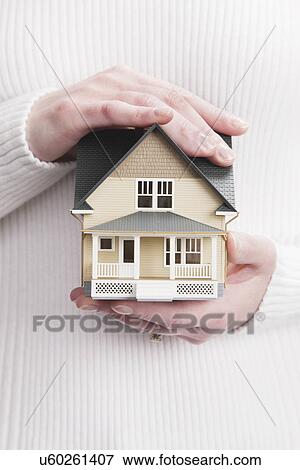 Stock Photo - Close up of woman's hands holding model house. Fotosearch