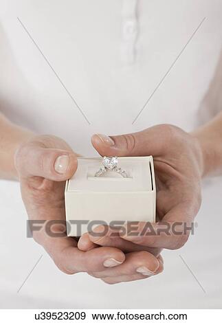Stock Photo - Close-up of woman's hands holding diamond ring in box. Fotosearch