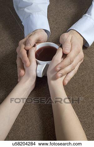 Picture - Close-up of young couple hand's holding tea cup together. Fotosearch
