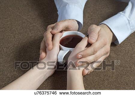 Close-up of young couple hand's holding tea cup together View Large Photo Image Stock Photograph - Close-up of young couple hand's holding tea cup together. Fotosearch