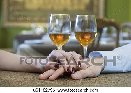 Close-up of young couple hand's on restaurant table with white wine glasses in background View Large Photo Image Stock Photography - Close-up of young couple hand's on restaurant table with white wine glasses in background. Fotosearch