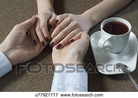 Close-up of young couple holding hands beside tea cup View Large Photo Image Stock Photo - Close-up of young couple holding hands beside tea cup. Fotosearch