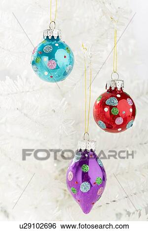 Stock Photograph - Colorful Christmas ornaments hanging on white Christmas tree. Fotosearch