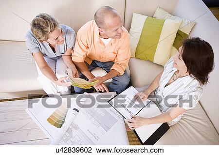 Couple and interior designer sitting on sofa and choosing color sample, high angle view View Large Photo Image Stock Image - Couple and interior designer sitting on sofa and choosing color sample, high angle view. Fotosearch
