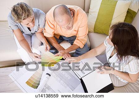 Couple and interior designer sitting on sofa and choosing color sample, high angle view View Large Photo Image Stock Photo - Couple and interior designer sitting on sofa and choosing color sample, high angle view. Fotosearch