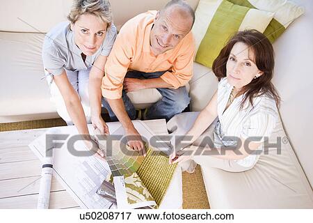 Couple and interior designer sitting on sofa and choosing color sample, portrait, high angle view View Large Photo Image Stock Photo - Couple and interior designer sitting on sofa and choosing color sample, portrait, high angle view. Fotosearch