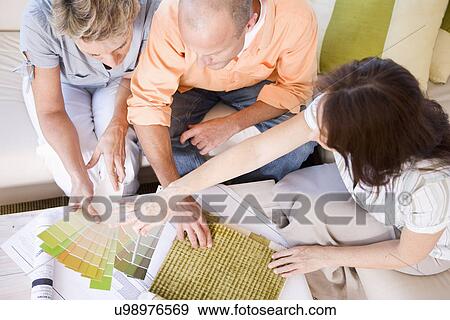 Stock Photo - Couple and interior designer sitting on sofa and choosing color sample, high angle view. Fotosearch