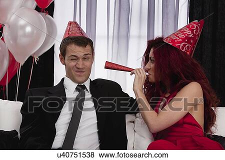 Couple celebrating birthday by playing with paper blow horns View Large Photo Image Stock Photo - Couple celebrating birthday by playing with paper blow horns. Fotosearch