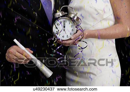 Stock Photo - Couple holding alarm clock showing fraction of minute to New Year. Fotosearch