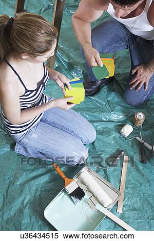 Couple looking at color samples in drop cloth covered room View Large Photo Image Stock Photography - Couple looking at color samples in drop cloth covered room. Fotosearch