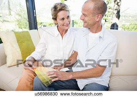 Couple on sofa choosing color samples, sitting face to face, smiling View Large Photo Image Stock Image - Couple on sofa choosing color samples, sitting face to face, smiling. Fotosearch