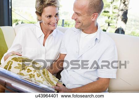 Couple on sofa holding fabric swatches, sitting face to face, smiling View Large Photo Image Stock Image - Couple on sofa holding fabric swatches, sitting face to face, smiling. Fotosearch