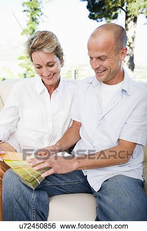 Stock Photograph - Couple on sofa looking at color samples, smiling. Fotosearch