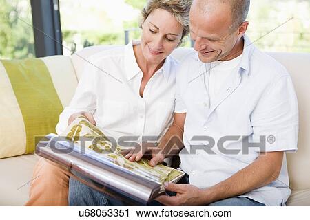 Stock Image - Couple on sofa looking at fabric swatches, smiling. Fotosearch