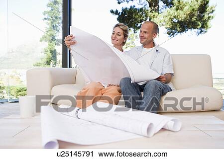 Couple sitting on sofa with blueprints in foreground View Large Photo Image Stock Image - Couple sitting on sofa with blueprints in foreground. Fotosearch