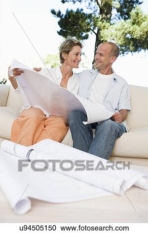 Couple sitting on sofa with blueprints in foreground View Large Photo Image Stock Image - Couple sitting on sofa with blueprints in foreground. Fotosearch