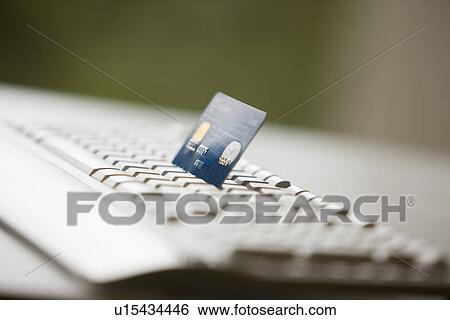 Stock Photograph - Credit card put in computer keyboard, close-up. Fotosearch