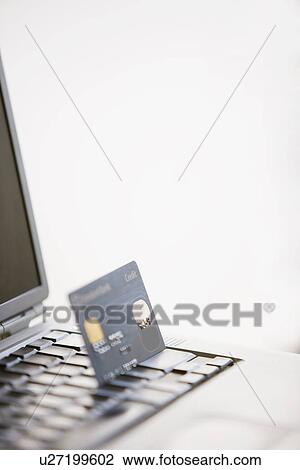 Stock Image - Credit card put in laptop keyboard, close-up. Fotosearch