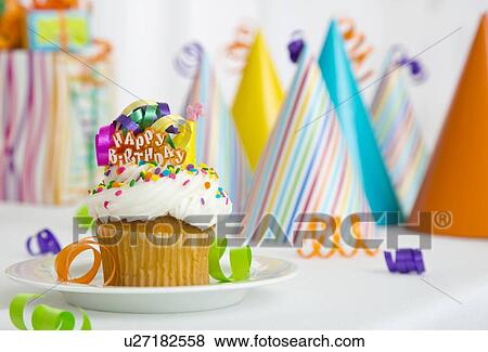 Stock Photo - Cupcake, party hats in background. Fotosearch