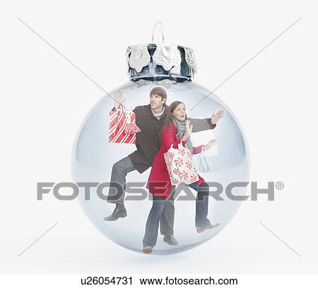 Stock Image - Digital composite of panic people with shopping bags inside christmas bulb. Fotosearch