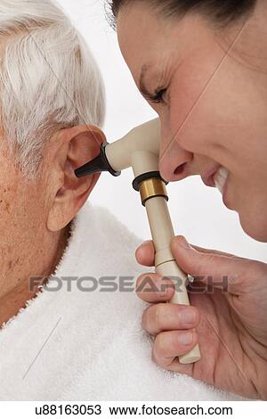 Stock Image - Doctor examining senior patient's ear. Fotosearch